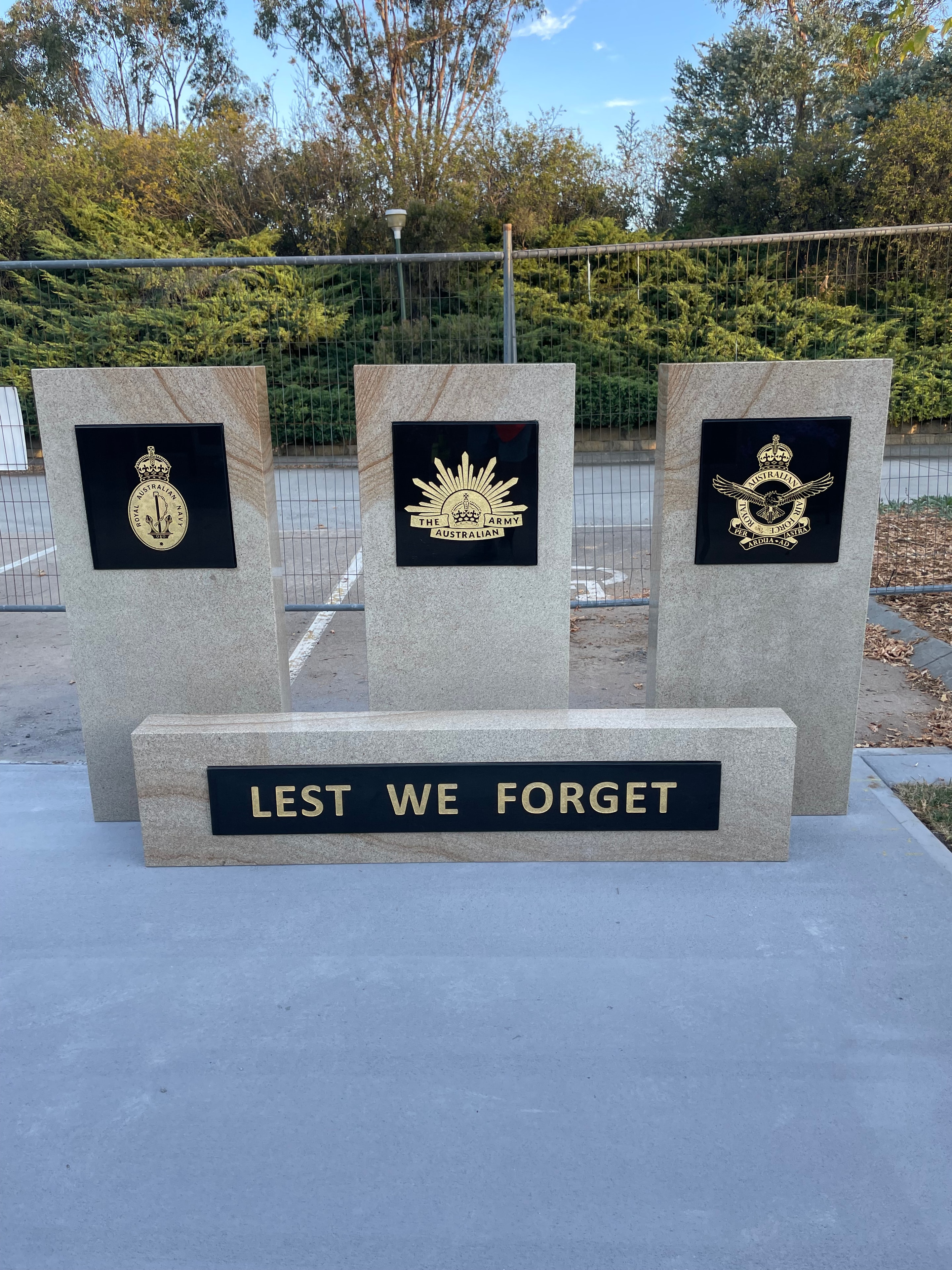 Lest We Forget memorial with three service emblems